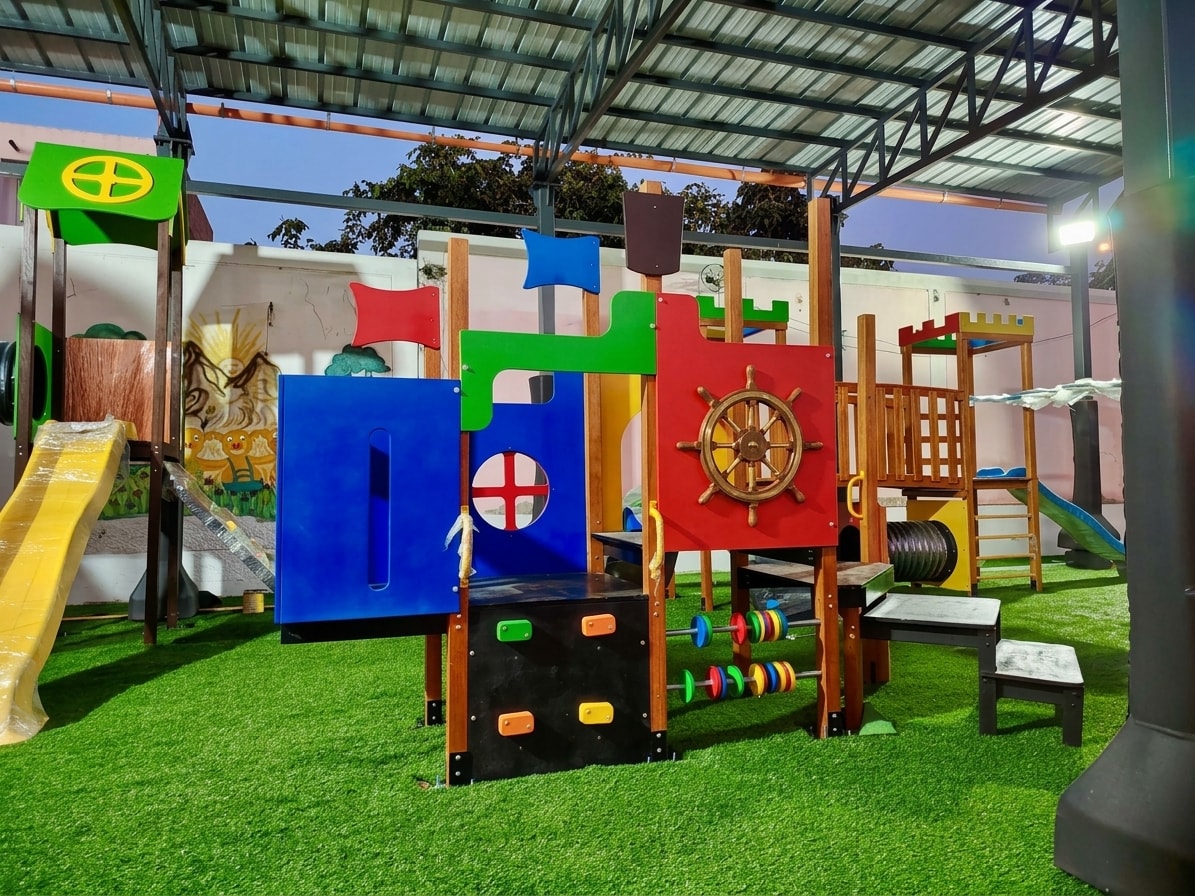 Módulo combinado de madera con temática pirata instalado en patio con pasto sintético