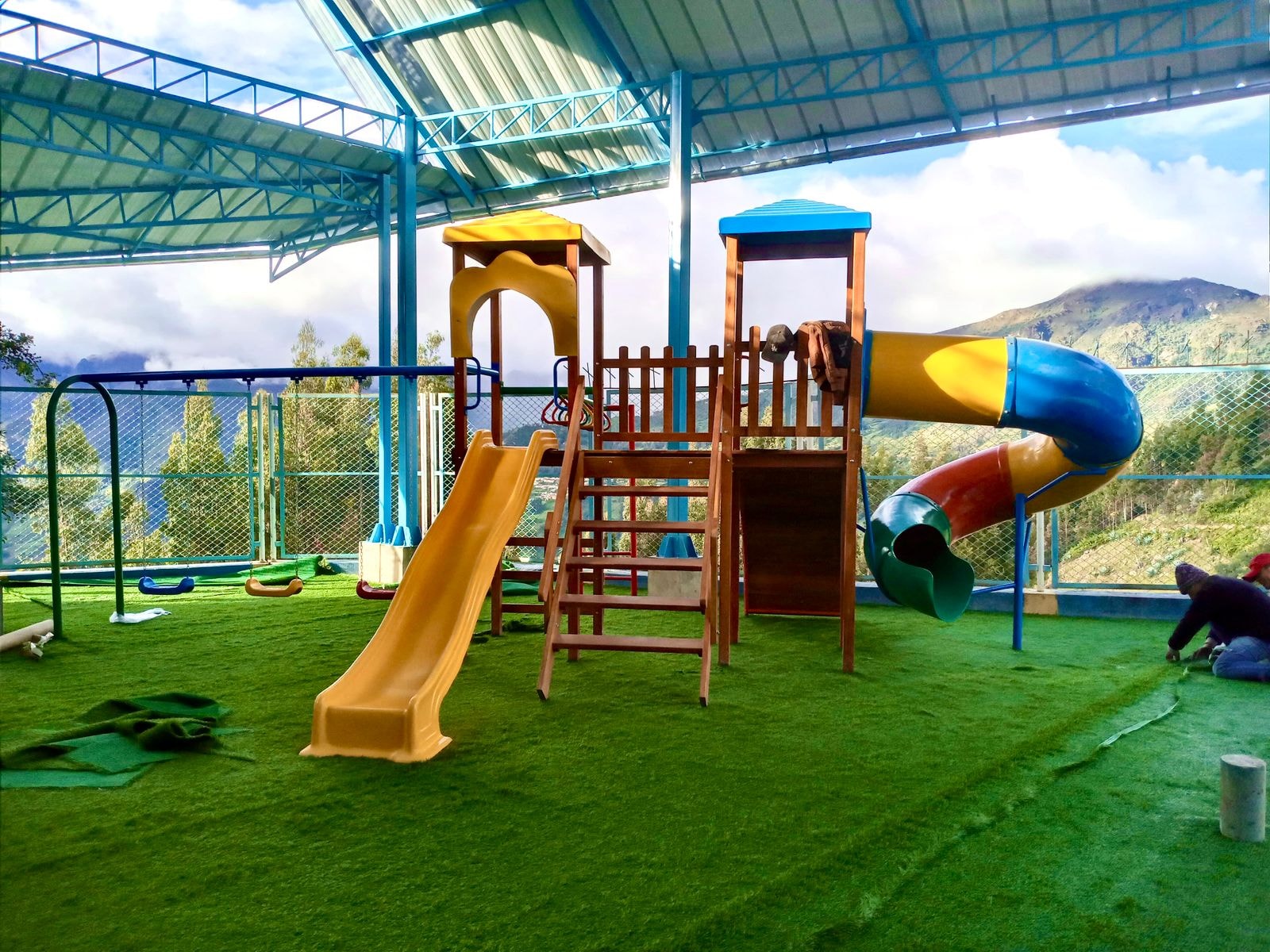 Juego combinado con tobogán y columpios instalado en terraza con vista a montañas