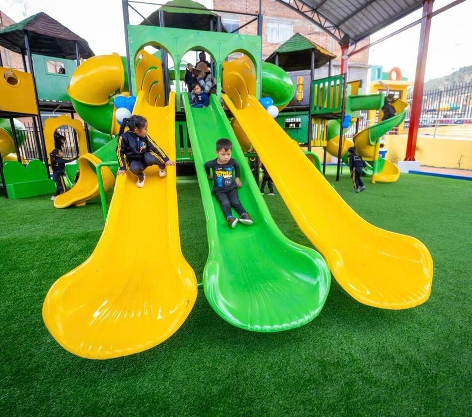 Niños disfrutando toboganes de fibra de vidrio en un parque instalado por Príncipe Kids